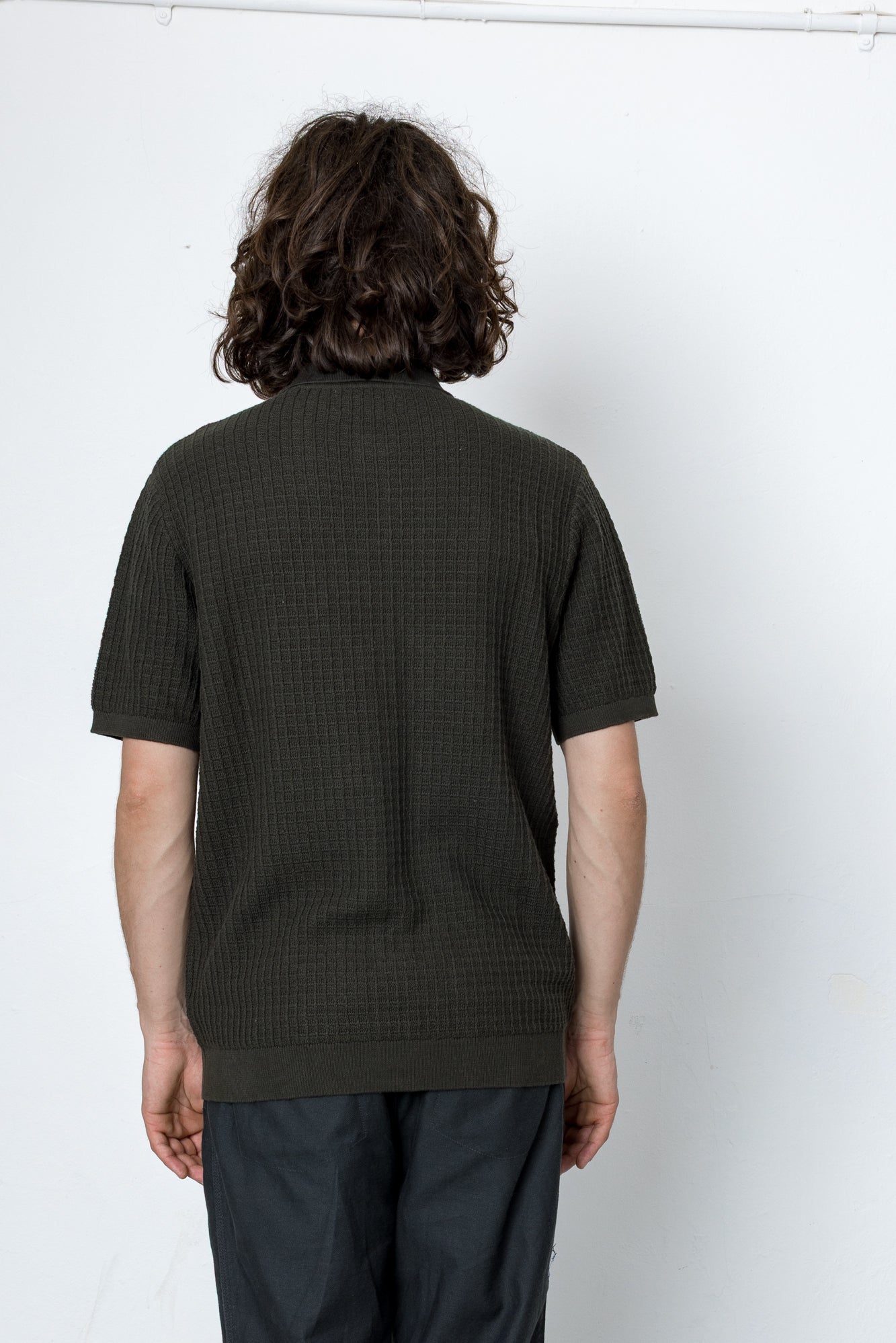 Person wearing a dark green textured shirt against a white background