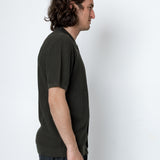 Man wearing a dark green textured shirt against a white background