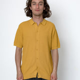 Man wearing a mustard yellow shirt against a white background