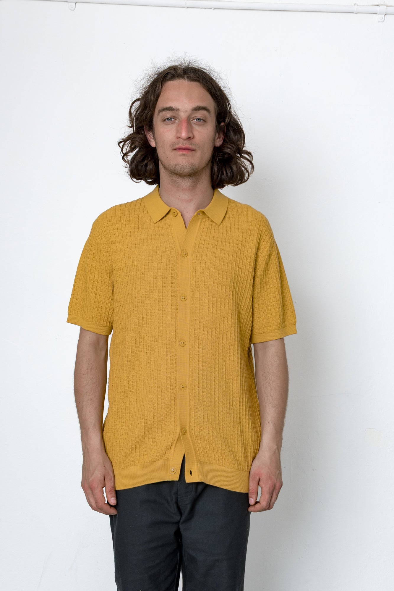 Man wearing a mustard yellow shirt against a white background