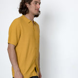 Man wearing a mustard yellow shirt against a white background