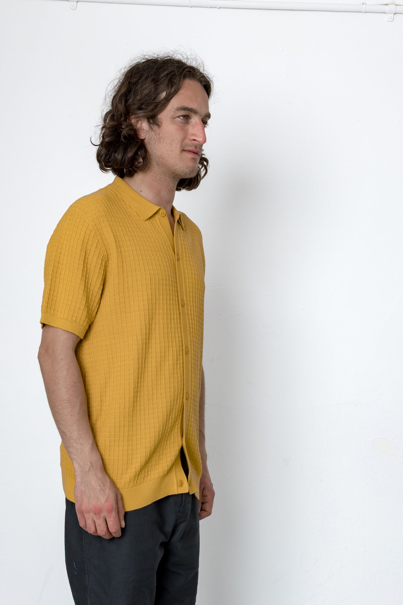 Man wearing a mustard yellow shirt against a white background
