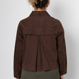 Person wearing a brown jacket and green pants against a white background