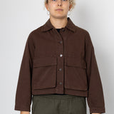 Person wearing a brown jacket and green pants on a white background