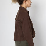 Person wearing a brown jacket and green pants on a white background