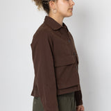 Person wearing a brown jacket and green pants against a white background