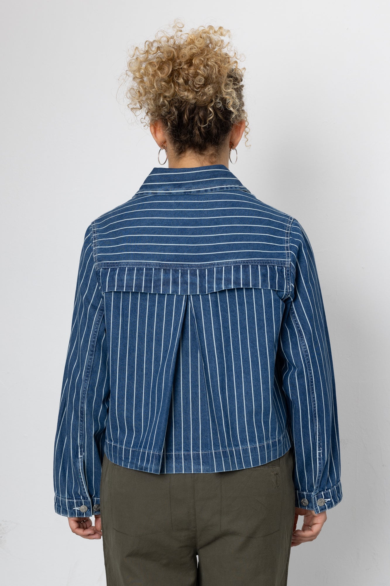 Person wearing a blue striped shirt against a white background