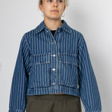 Person wearing a blue striped denim jacket against a white background