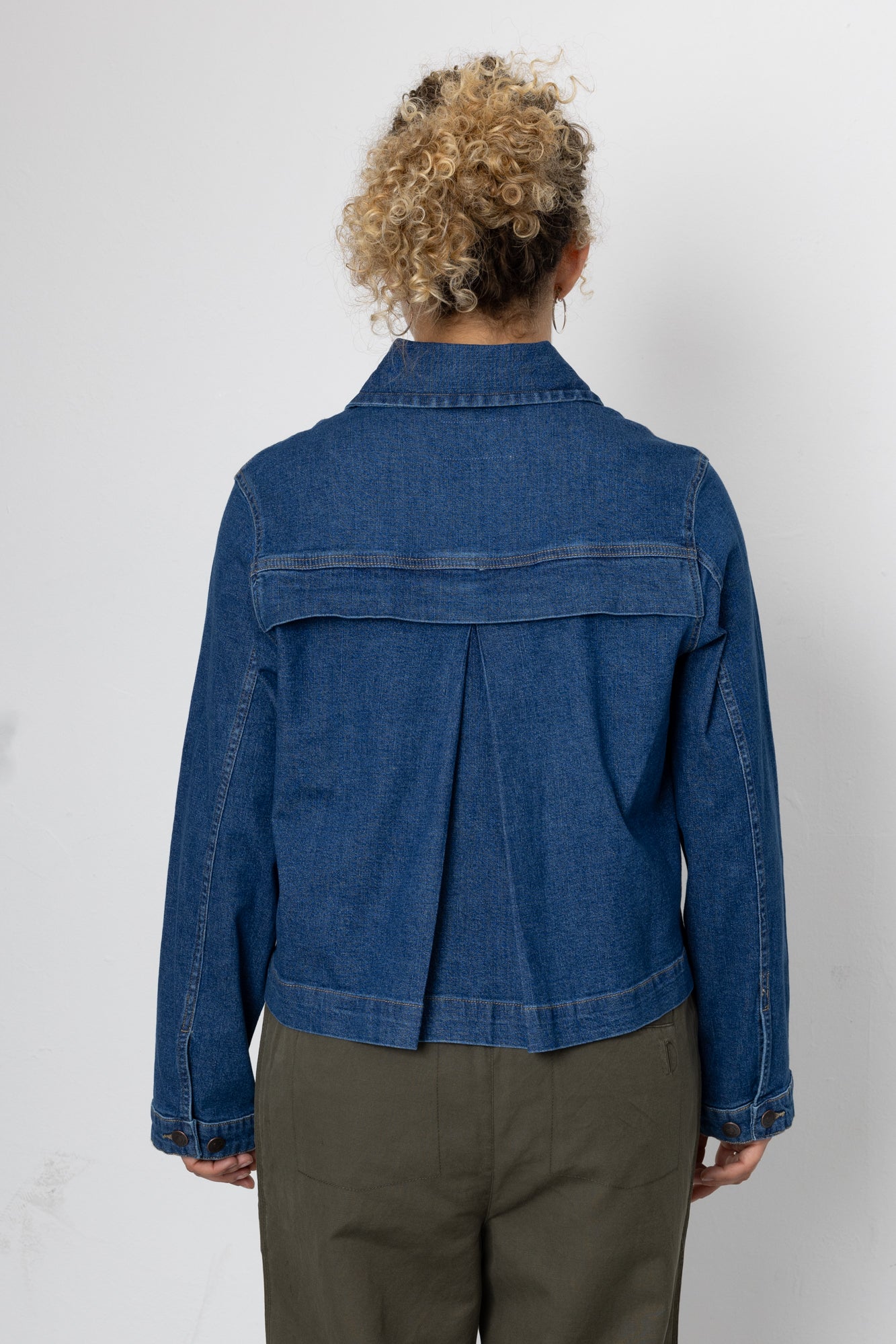 Person wearing a blue denim jacket on a white background