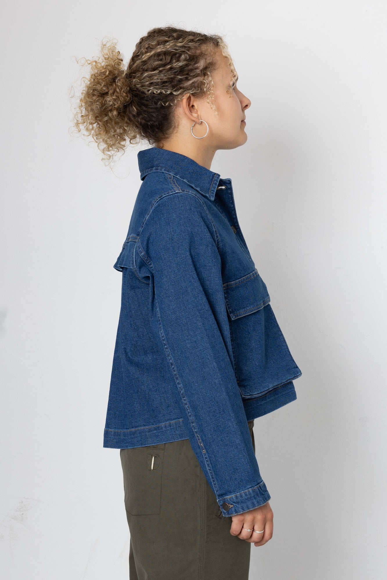 Person wearing a blue denim jacket on a white background