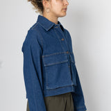Person wearing a blue denim jacket against a plain background