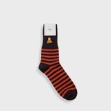 A single sock with horizontal orange and black stripes, a black toe and heel, and a small gold geometric logo near the cuff, shown on a light gray background with a white paper label attached.