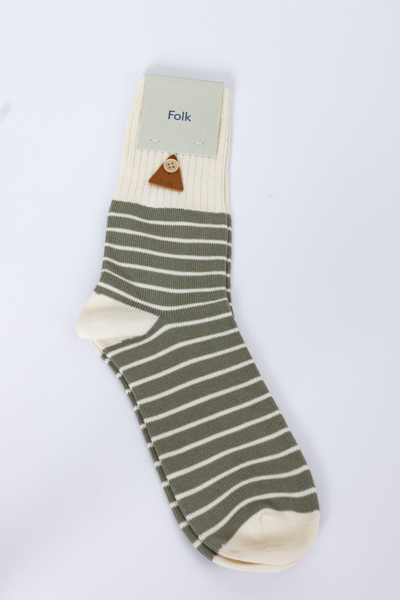 Green and beige striped sock with 'Folk' label on a white background