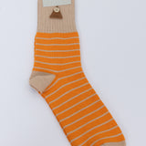 Orange striped sock against a grey background