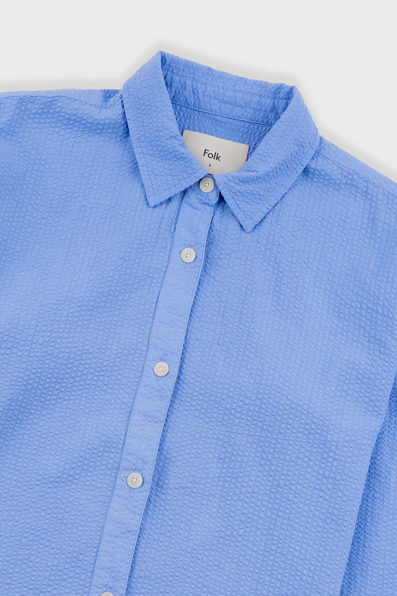 Blue textured shirt with collar and buttons on a white background