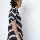 Man wearing a striped shirt standing against a white wall