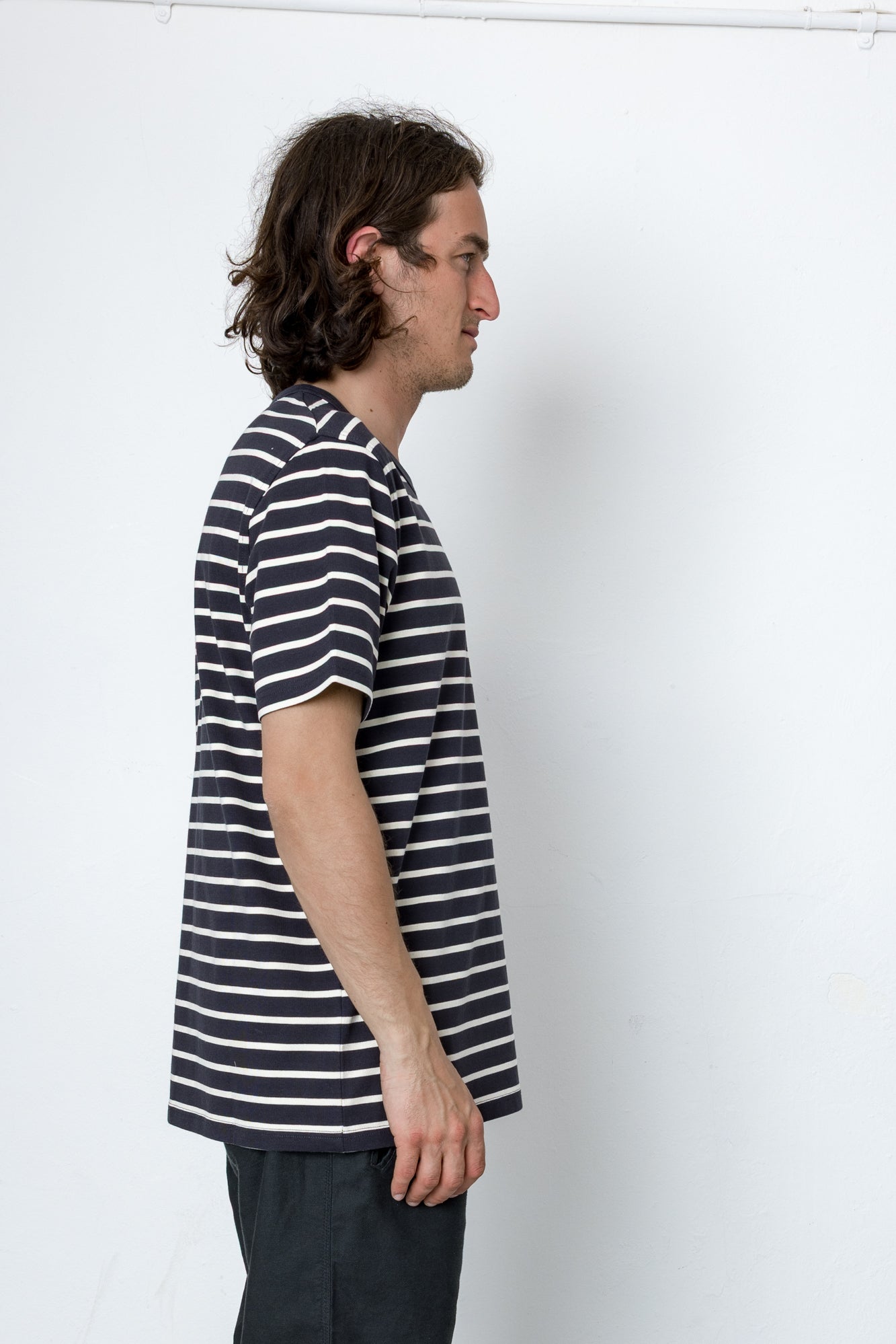 Man wearing a striped shirt standing against a white wall