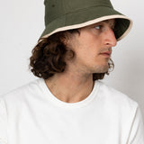 Person wearing a green bucket hat against a white background