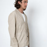 Man wearing a beige jacket over a white shirt on a white background