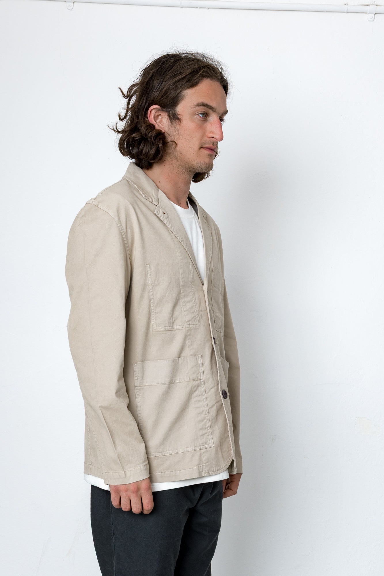 Man wearing a beige jacket over a white shirt on a white background