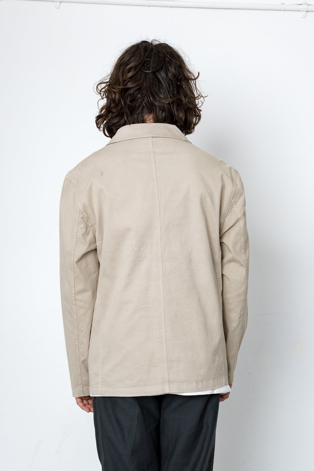 Person wearing a beige jacket with a plain white background