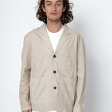 Man wearing a beige jacket over a white shirt on a white background