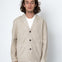 Man wearing a beige jacket over a white shirt on a white background