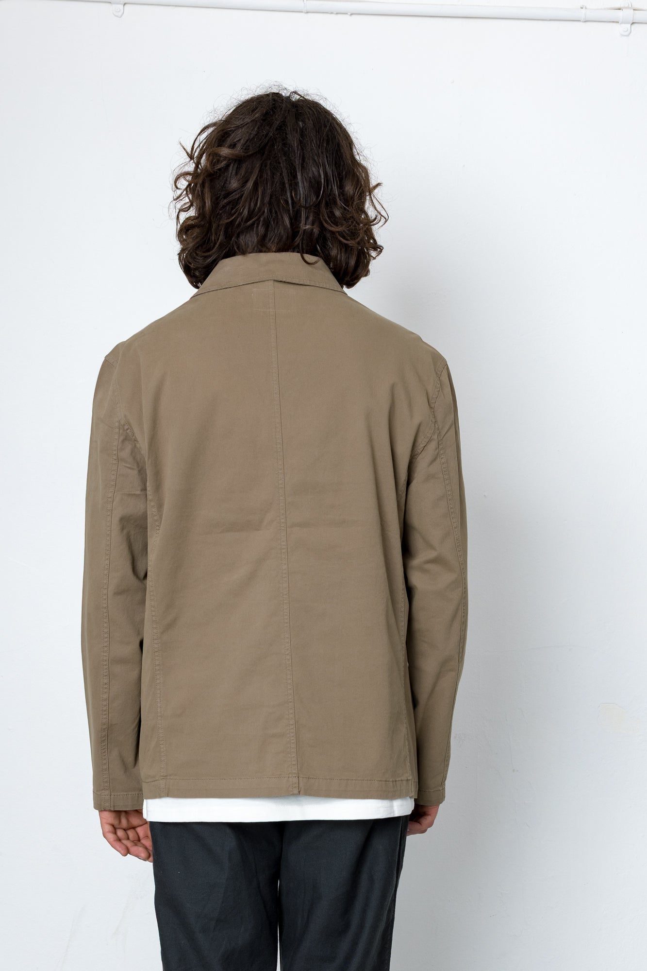 Person wearing a beige jacket against a white background