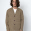 Man wearing a beige jacket over a white shirt on a white background