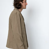 Person wearing a beige jacket against a white background
