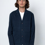 Man wearing a navy blue jacket over a white shirt on a white background