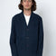 Man wearing a navy blue jacket over a white shirt on a white background