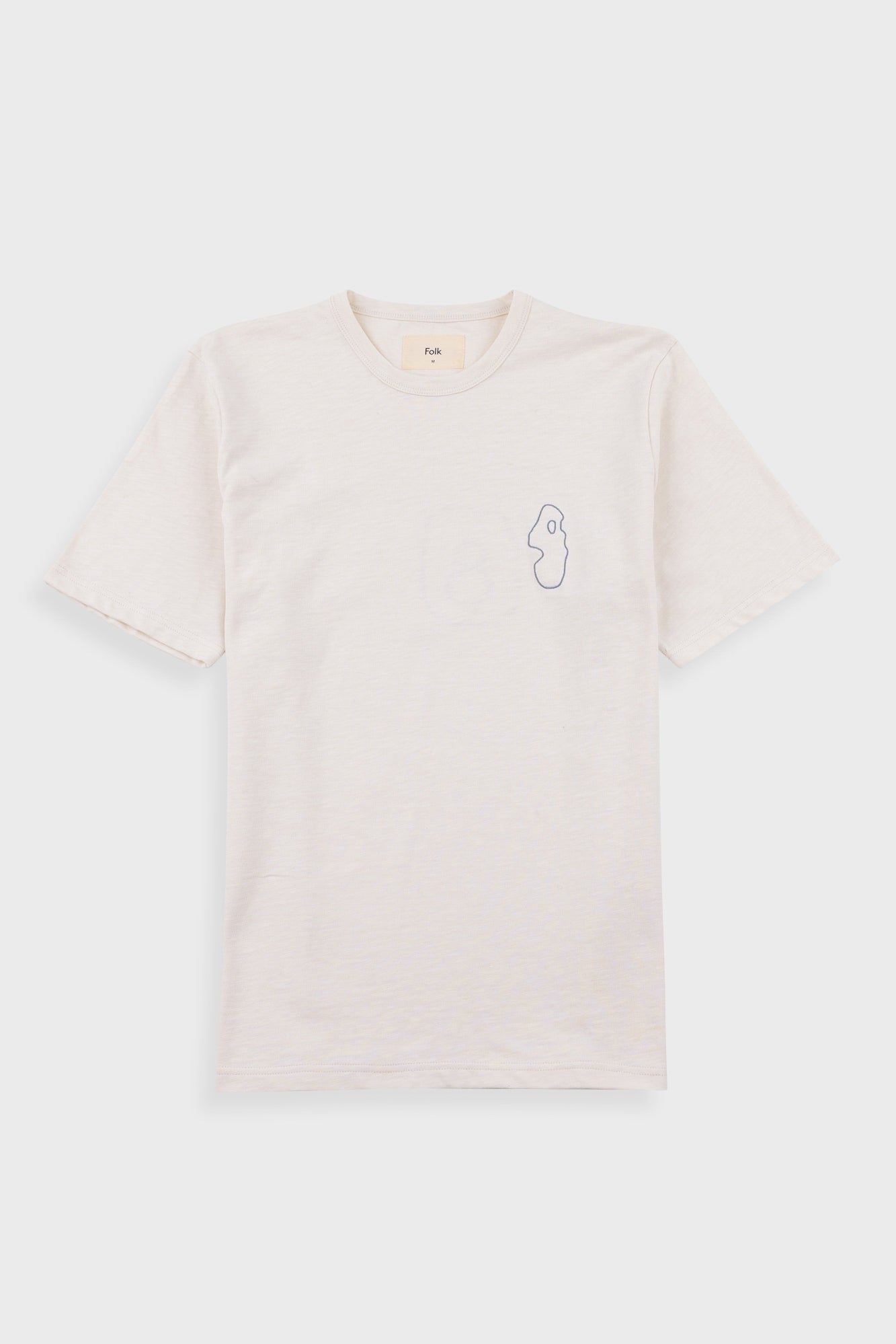 A light cream-colored short-sleeve t-shirt with a small, minimalist line-art profile graphic on the left chest, displayed flat against a light gray background.