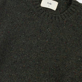 Dark green sweater with a visible brand label on a light gray background