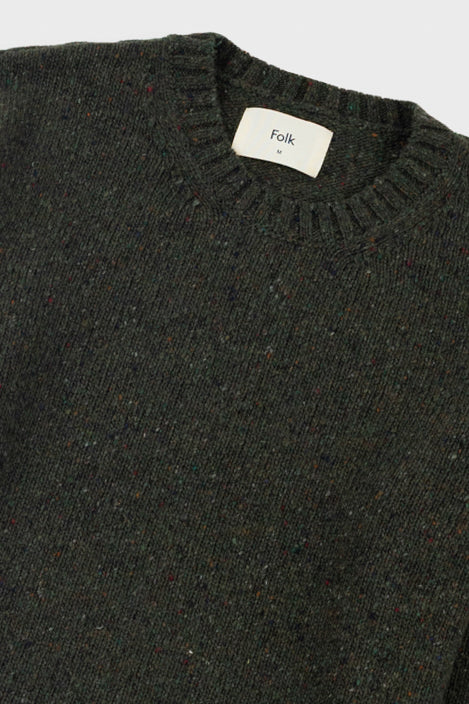 Dark green sweater with a visible brand label on a light gray background