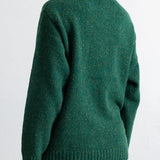 A woman wearing a textured green knit sweater, shown from the back against a plain white background.