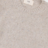 Close up of a cream coloured knitted jumper, showing the ribbed detailing on the crew neckline
