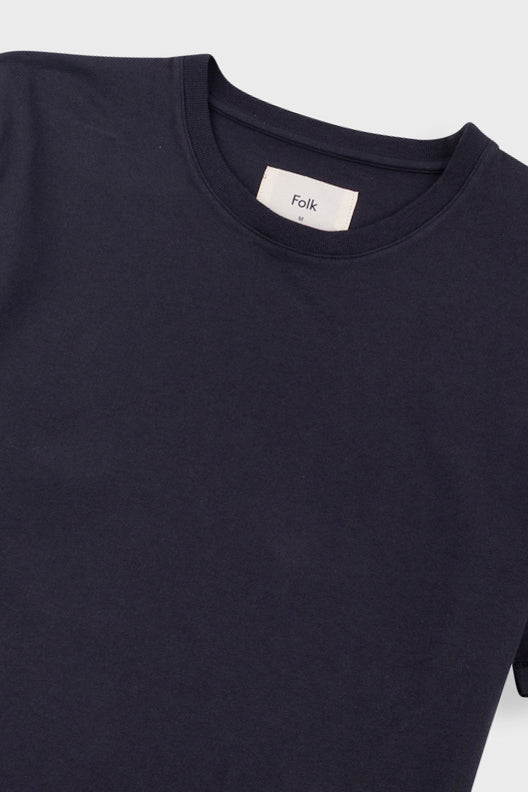 Close-up of a dark navy crewneck t-shirt with a white neck label reading 'Folk'.