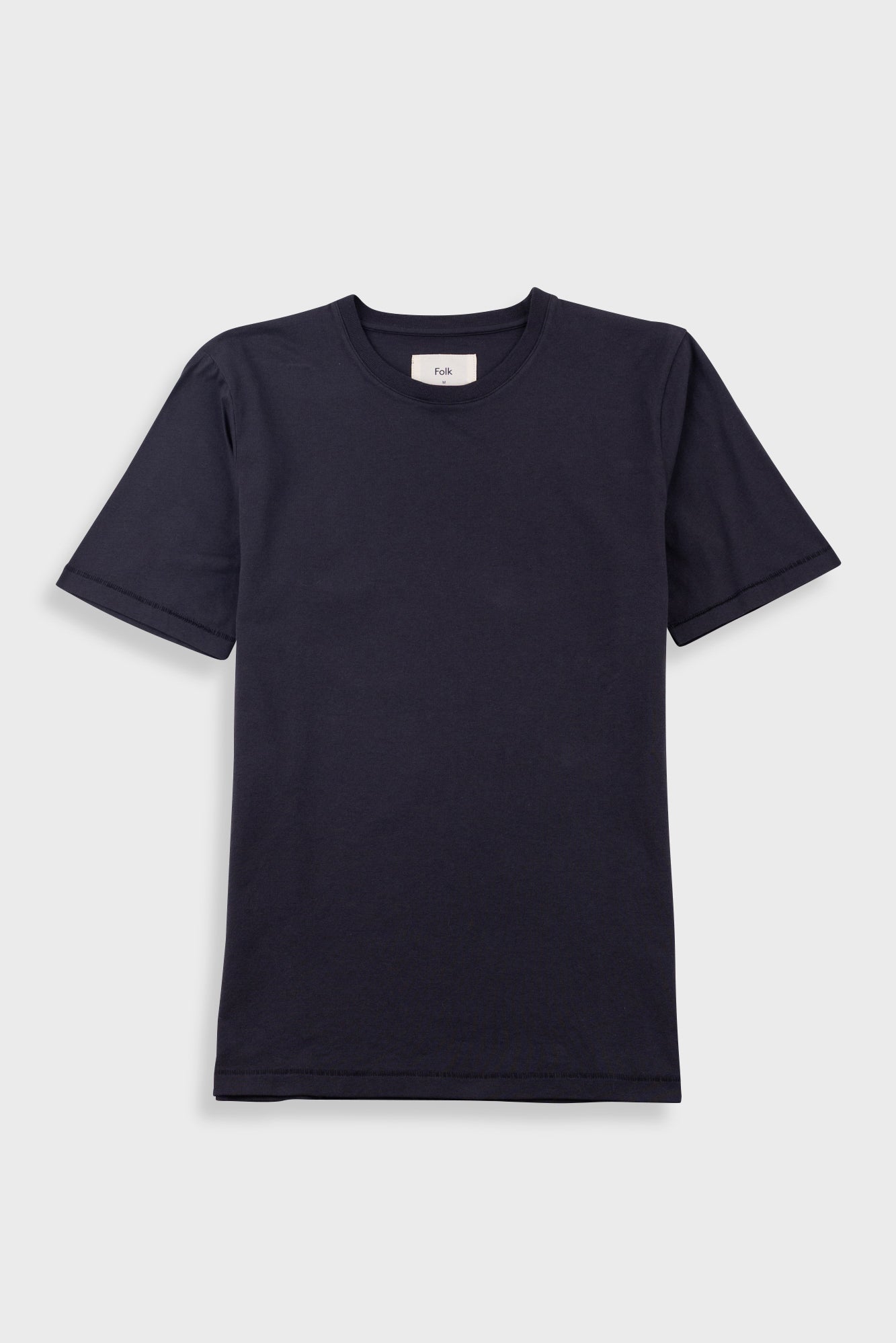 Close-up of a dark navy crewneck t-shirt with a white neck label reading 'Folk'.
