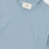 Close-up of a light blue crewneck t-shirt with a white neck label reading 'Folk'.