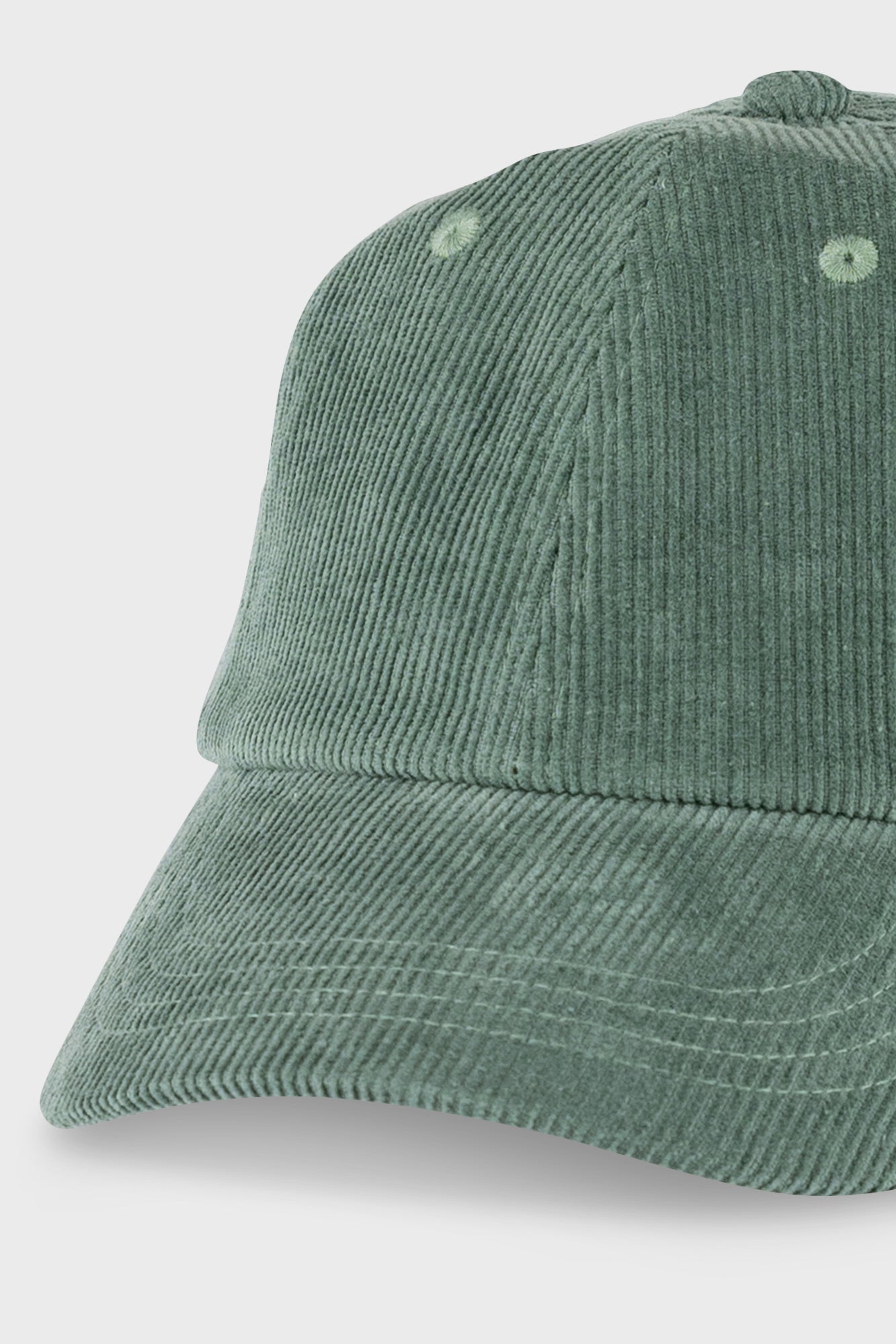 A close-up of a sage green corduroy baseball cap on a light gray background.