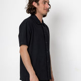 Man wearing a black short-sleeve shirt against a white background