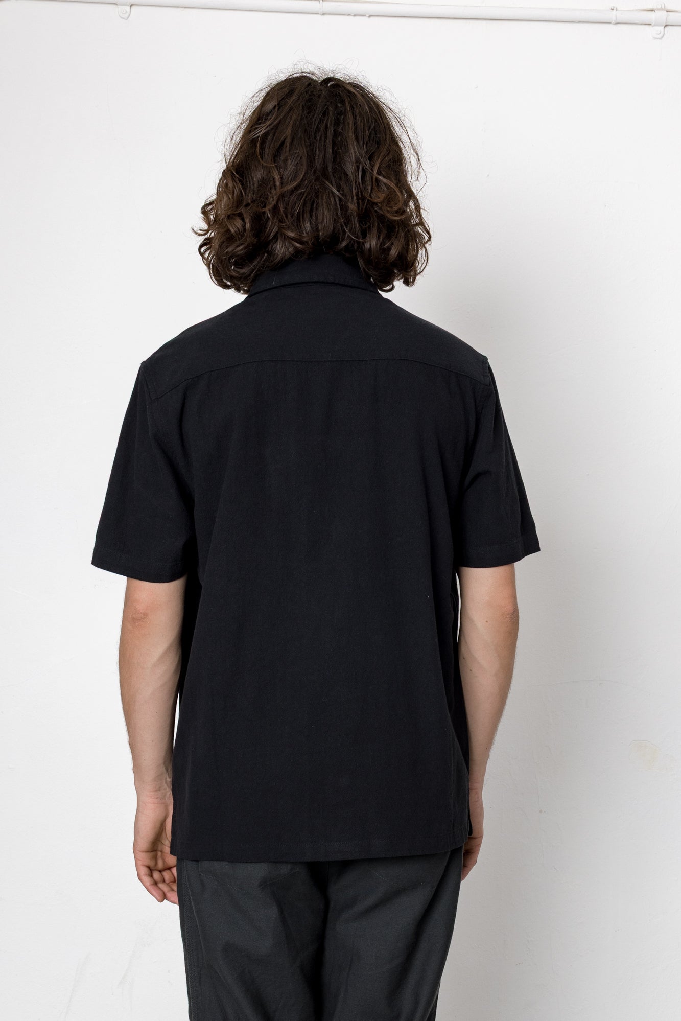 Person wearing a black shirt and pants against a white background