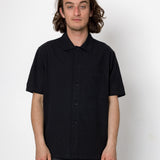 Man wearing a black short-sleeve shirt against a white background