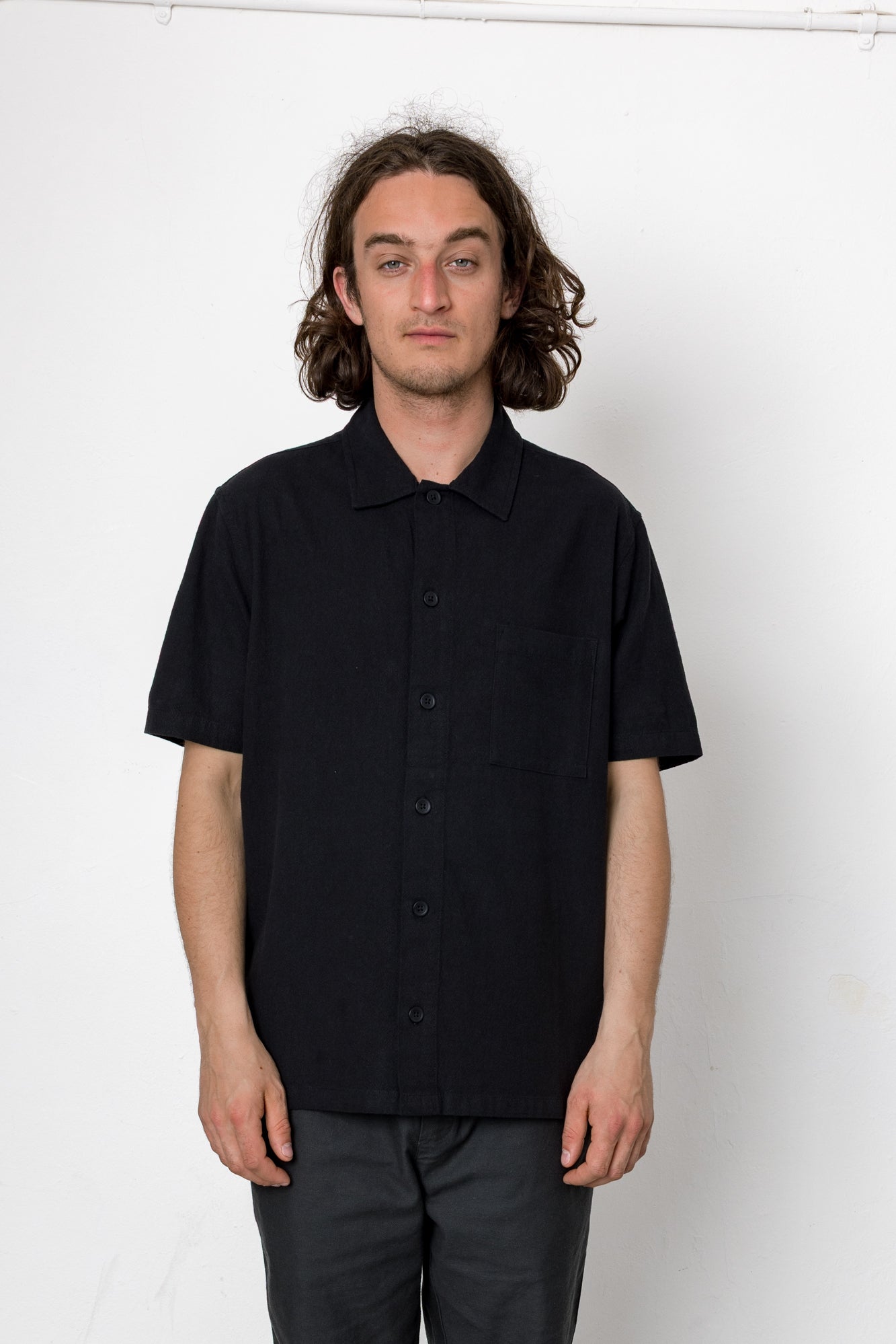Man wearing a black short-sleeve shirt against a white background