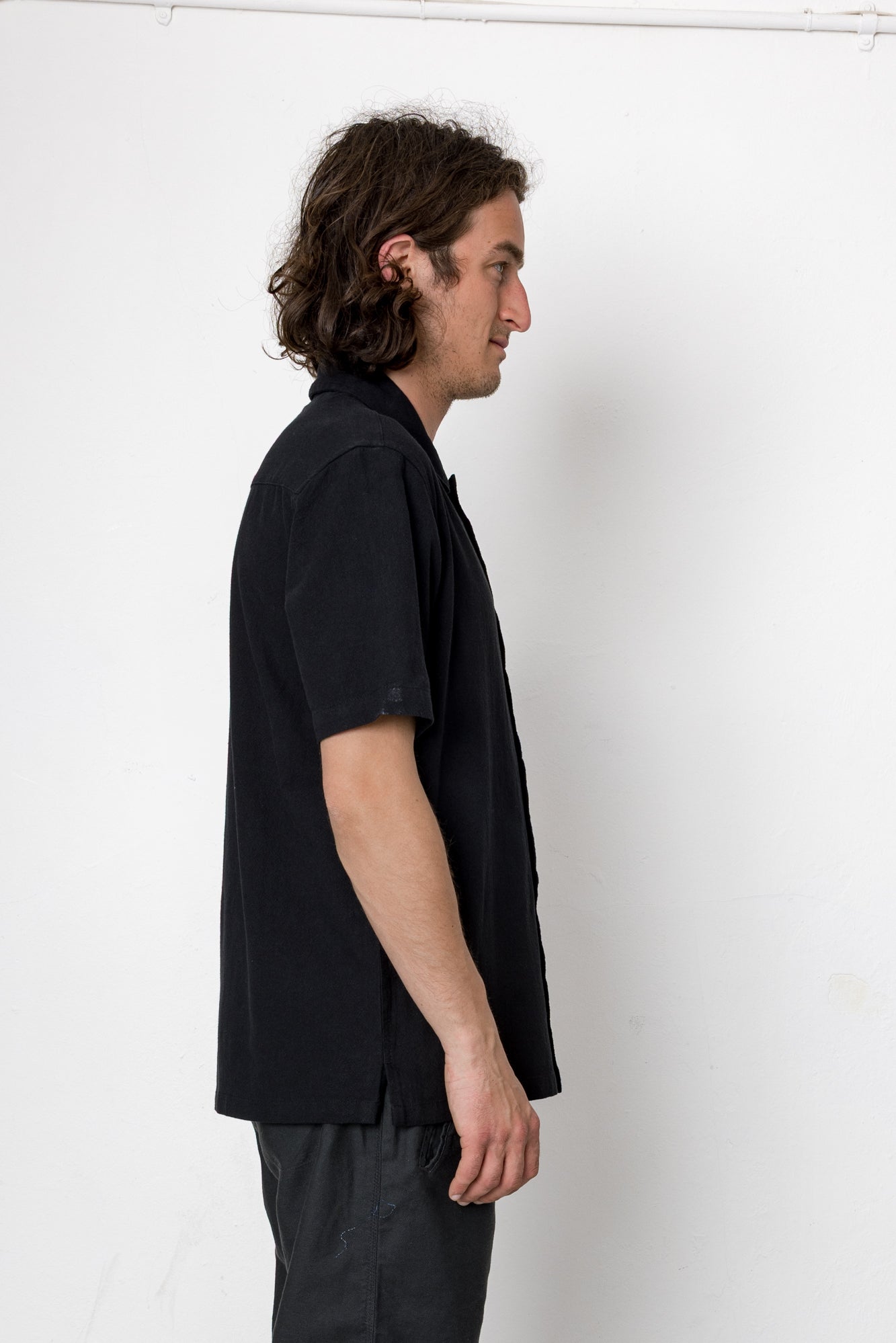 Man wearing a black shirt and pants against a white background