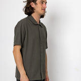 Man wearing a green shirt and black pants against a white background