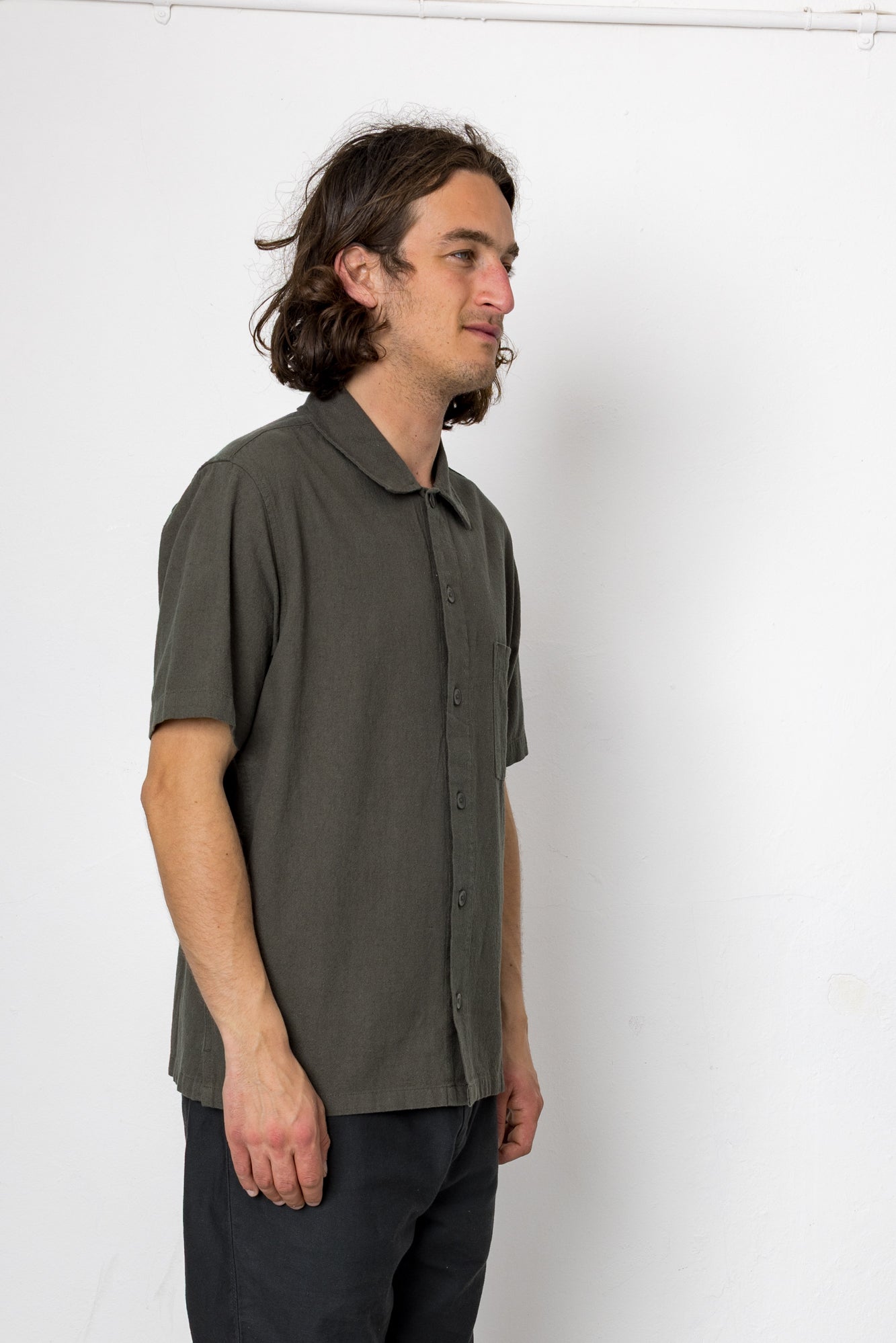 Man wearing a green shirt and black pants against a white background