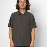 Man wearing a dark green short-sleeve shirt against a white background