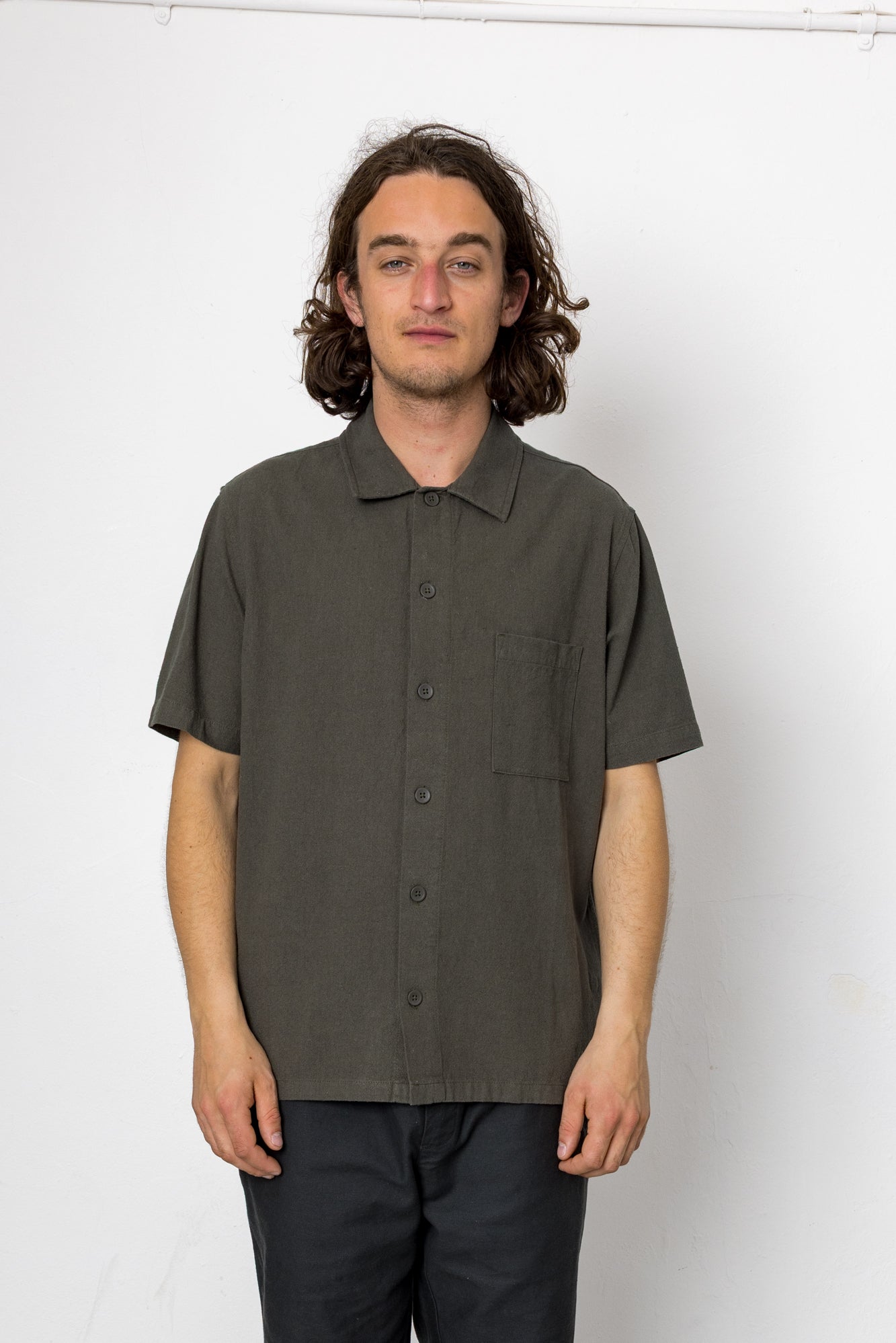 Man wearing a dark green short-sleeve shirt against a white background
